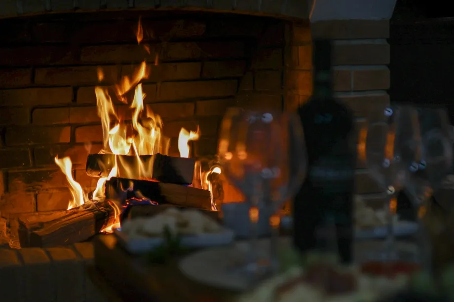 Logs burning in a brick fireplace with a softly lit table in the background